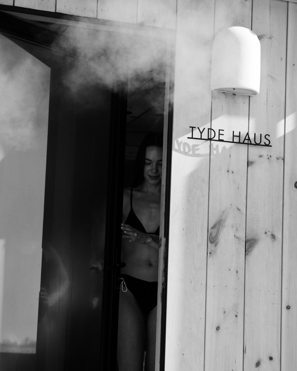 Steam pouring from the sauna door beside the TYDE HAUS sign.